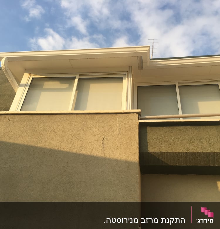 גג עם מרזב לבן וחלונות זכוכית